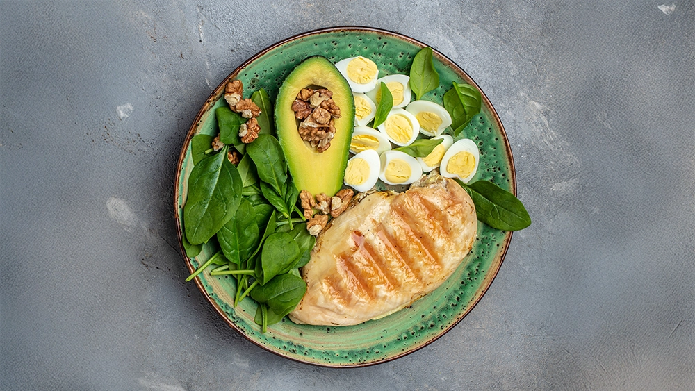 low-carb-high-fat-breakfast-ketogenic-diet-avocado-grilled-chicken-fillet-quail-egg-spinach-walnut-long-banner-format-top-view